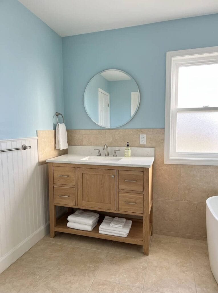Bathroom with coastal blue painted wall and warm wood vanity