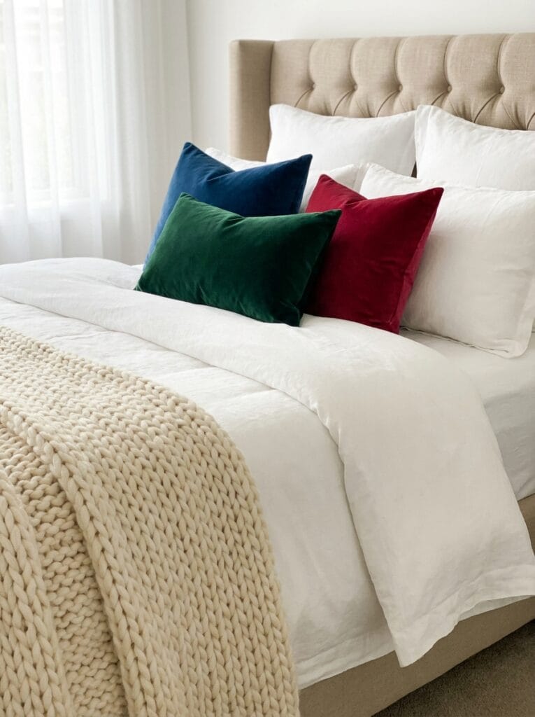 Luxury bedroom bedding with layered linen sheets, knit throw, and velvet pillows