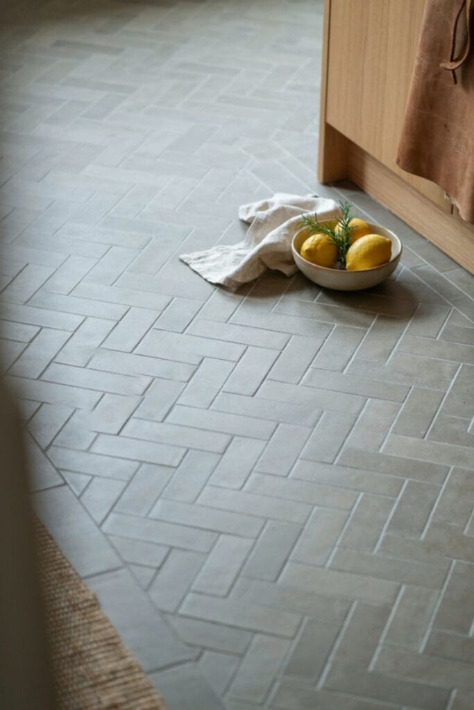 Soft gray herringbone pattern kitchen tile floor idea